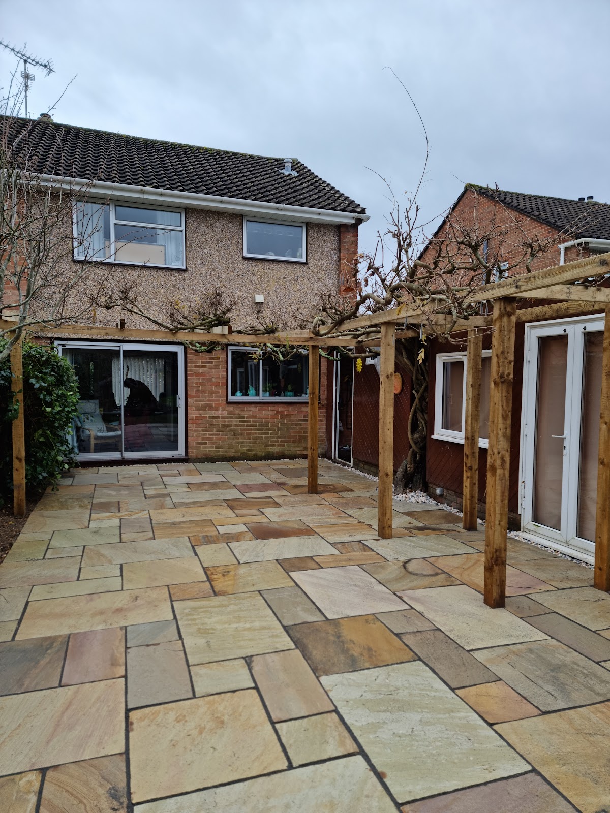 Indian sandstone patio laid beneath a mature pergola